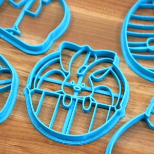 May include: Five blue plastic cookie cutters shaped like Easter eggs, a bunny in an egg, a bunny, and two other shapes.