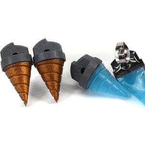 May include: A set of four earrings. Two are a metallic bronze color with a gray top, and two are a translucent blue with a black top. The earrings are shaped like a drill bit.