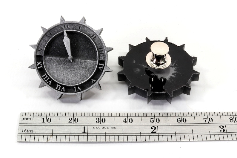 Puede incluir: Dos pines de metal de color plateado con forma de esfera de reloj y un dise&ntilde;o de engranaje. El pin de esfera de reloj de la izquierda muestra la hora 11:55. El pin de esfera de reloj de la derecha tiene un respaldo de pin de color plateado.