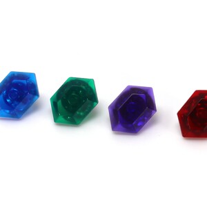 May include: Four plastic gems in different colors: blue, green, purple, and red. The gems are shaped like octagons with a raised center.