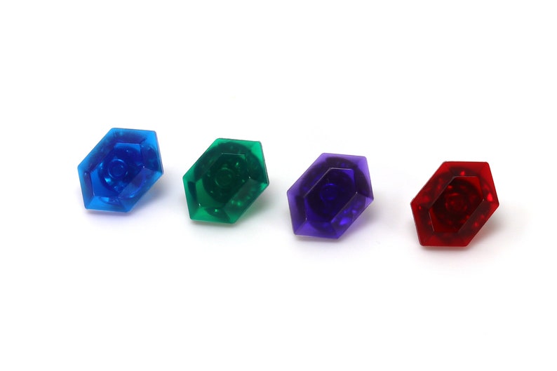 May include: Four plastic gems in different colors: blue, green, purple, and red. The gems are shaped like octagons with a raised center.