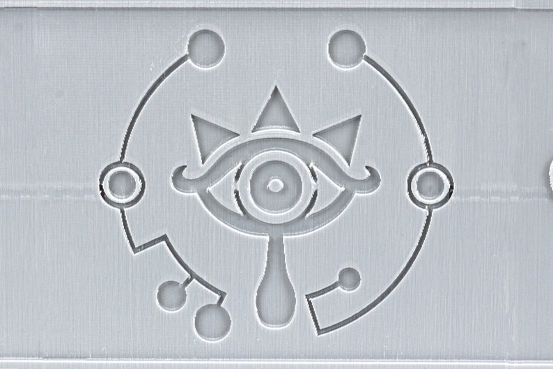 May include: A gray and white stylized eye with a teardrop shape below it. The eye is surrounded by a circle with five smaller circles around it.