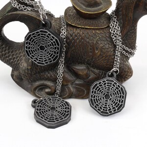 May include: Three silver necklaces with geometric pendant charms. The charms are octagonal and feature a detailed, intricate design.