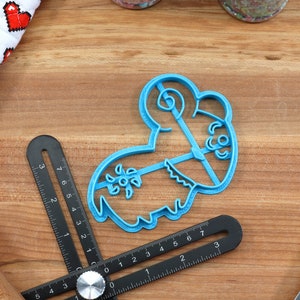 Puede incluir: Cortador de galletas de pl&aacute;stico azul con forma de oveja de dibujos animados con un dise&ntilde;o floral en el lateral.
