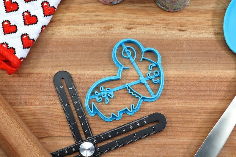 Puede incluir: Cortador de galletas de pl&aacute;stico azul con forma de oveja de dibujos animados con un dise&ntilde;o floral en el lateral.