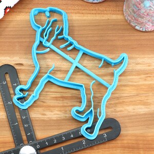 May include: A blue plastic cookie cutter shaped like a dog. The cutter is approximately 6 inches long and 4 inches wide.