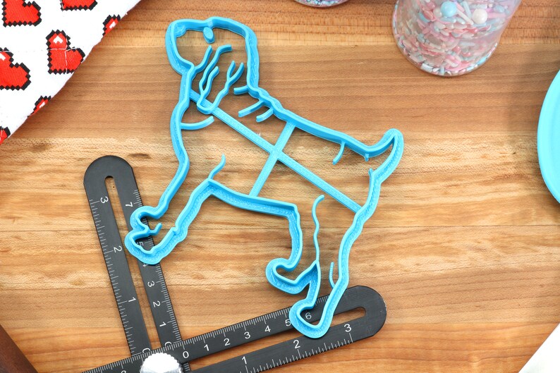 May include: A blue plastic cookie cutter shaped like a dog. The cutter is approximately 6 inches long and 4 inches wide.
