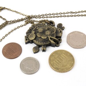 May include: A bronze necklace with a detailed steampunk-style pendant featuring a cartoon lion face surrounded by gears and other mechanical elements. The pendant is hanging with a chain and is surrounded by four coins.