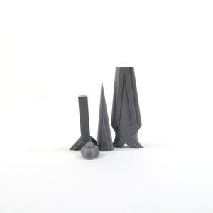 May include: Four gray 3D printed objects, including a cone, a tall rectangular shape with a pointed top, and two shorter rectangular shapes with pointed tops.