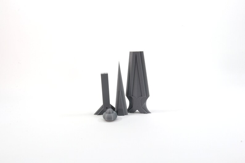 May include: Four gray 3D printed objects, including a cone, a tall rectangular shape with a pointed top, and two shorter rectangular shapes with pointed tops.