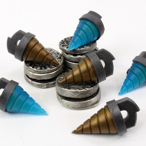 May include: A collection of miniature drill bits with a metallic gray collar and a brown or blue translucent tip. The drill bits are arranged on small, silver-colored, coin-like platforms. The overall aesthetic is industrial and futuristic.