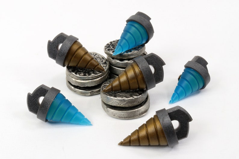 May include: A collection of miniature drill bits with a metallic gray collar and a brown or blue translucent tip. The drill bits are arranged on small, silver-colored, coin-like platforms. The overall aesthetic is industrial and futuristic.