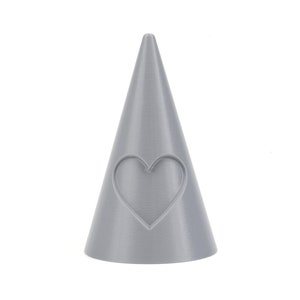 May include: A gray ceramic ring holder shaped like a cone with a heart cutout on the front.