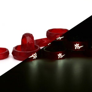 May include: Five red glow-in-the-dark silicone rings with a white design. The rings are stacked on top of each other in the dark, showing the glow-in-the-dark effect. The rings are also shown individually on a white background.