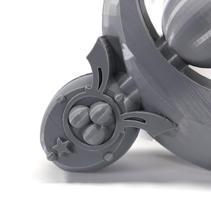 May include: A gray 3D printed object with a star and three spheres in a circular design. The object has a curved shape and a decorative design.