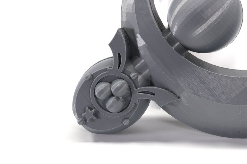 May include: A gray 3D printed object with a star and three spheres in a circular design. The object has a curved shape and a decorative design.