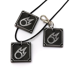 May include: Three silver and black metal pendants with a flame design. The pendants are on a black cord and a silver key chain.