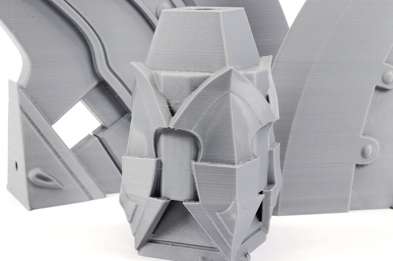 Puede incluir: Un modelo 3D impreso en gris de una forma geom&eacute;trica con una base cuadrada y una parte superior puntiaguda. El modelo tiene un dise&ntilde;o complejo con m&uacute;ltiples capas y &aacute;ngulos.