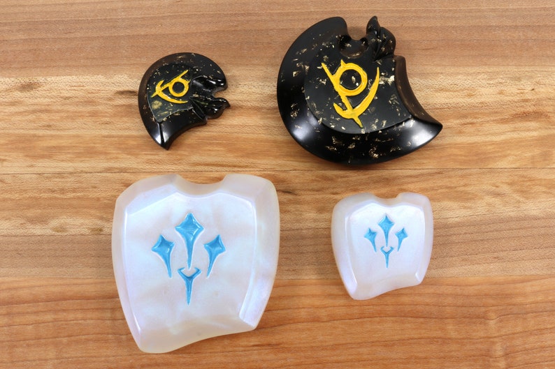 May include: Four decorative pieces with different designs. Two are white with a blue design, one is black with a gold design, and one is black with a gold design and is broken.