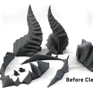 May include: Five gray 3D printed pieces of a fantasy terrain set, including two tall spires, a curved bridge, and two smaller pieces. The pieces are unpainted and have a rough, textured surface. Before Cleanup.