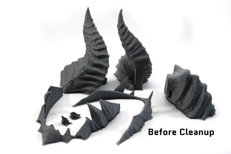 May include: Five gray 3D printed pieces of a fantasy terrain set, including two tall spires, a curved bridge, and two smaller pieces. The pieces are unpainted and have a rough, textured surface. Before Cleanup.