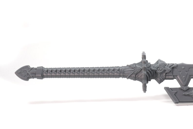 May include: A grey plastic sword with a detailed design. The sword has a sharp point and a decorative handle.