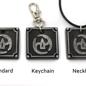 May include: Three silver-coloured metal pendants with a stylised symbol in the centre. The pendants are shown in three different styles: standard, keychain, and necklace.