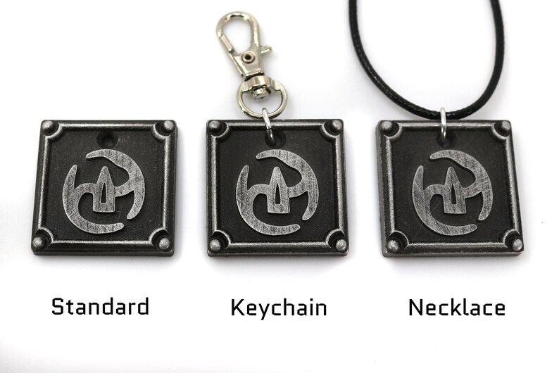 May include: Three silver-coloured metal pendants with a stylised symbol in the centre. The pendants are shown in three different styles: standard, keychain, and necklace.