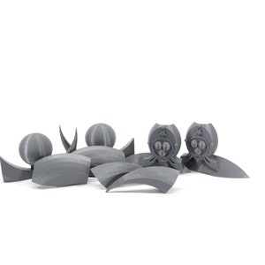 May include: A set of gray 3D printed plastic pieces for a model kit. The pieces include a sphere, a crescent shape, and two pieces with a star and three circles.