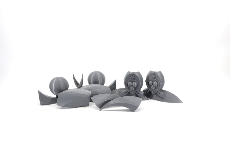 May include: A set of gray 3D printed plastic pieces for a model kit. The pieces include a sphere, a crescent shape, and two pieces with a star and three circles.