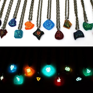 May include: A set of 15 necklaces with glow-in-the-dark pendants featuring various symbols and designs. The pendants are made of clear resin with embedded glitter and glow-in-the-dark powder. The necklaces are displayed on a white surface in the top image and in a dark room in the bottom image.