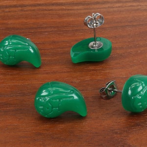 May include: A pair of green jade earrings in the shape of a teardrop with a silver post and butterfly back.