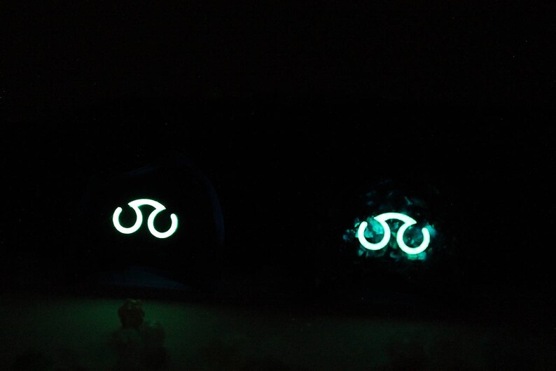May include: Two dark objects with a glowing green symbol of three interlocking circles. The symbol is a common symbol in fantasy and science fiction.