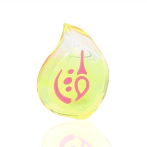 May include: A yellow teardrop-shaped glass charm with a pink swirl design inside.