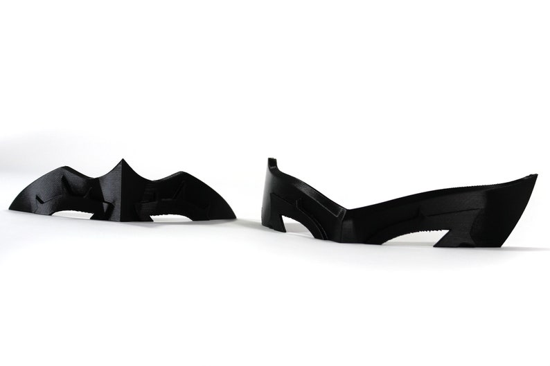May include: Two black plastic masks, one shaped like a bat and the other with a more angular design.