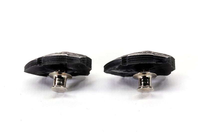May include: Two black metal buttons with a silver pin and post. The buttons are shaped like a leaf with a textured surface.