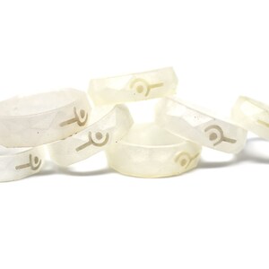 May include: A group of six white silicone rings with a raised design. The rings are stacked on top of each other.
