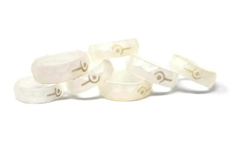 May include: A group of six white silicone rings with a raised design. The rings are stacked on top of each other.