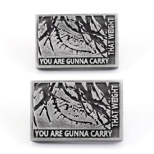 May include: Two silver metal pins with a distressed, textured design. The pins feature the text "You are gunna carry that weight" in black.