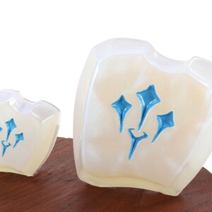 Pu&ograve; includere: Due scudi in ceramica bianca con un designo blu. Lo scudo pi&ugrave; grande &egrave; leggermente pi&ugrave; alto del pi&ugrave; piccolo. Entrambi gli scudi hanno un design stilizzato blu a tre punte.