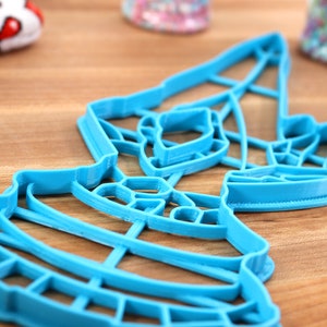 May include: A blue plastic cookie cutter shaped like a Christmas tree with a star on top.