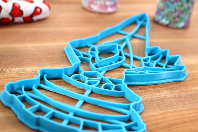 May include: A blue plastic cookie cutter shaped like a Christmas tree with a star on top.