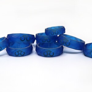 May include: A group of eight blue silicone rings with a geometric design and a symbol on the top.