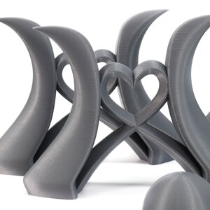 May include: A set of three gray 3D printed sculptures, each featuring a curved shape with a heart design in the center. The sculptures are arranged in a way that creates a sense of balance and harmony.
