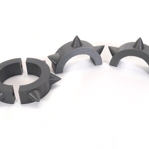 May include: Three grey plastic spiked rings, two are half circles and one is a full circle.