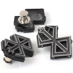 May include: Three silver-coloured metal pins with a geometric design. The pins are attached to black plastic bases.