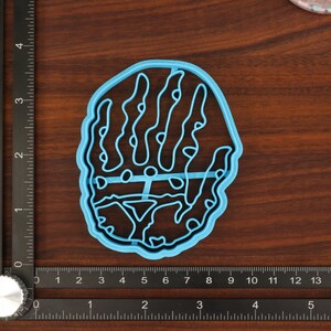 Puede incluir: Un cortador de galletas de pl&aacute;stico azul claro con forma de mano y un dise&ntilde;o detallado.