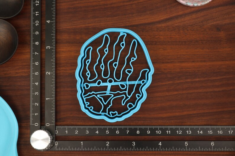 Puede incluir: Un cortador de galletas de pl&aacute;stico azul claro con forma de mano y un dise&ntilde;o detallado.