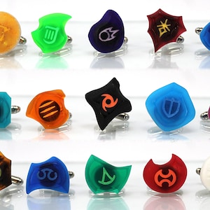 May include: Set of 15 colorful cufflinks featuring various symbols and designs. The cufflinks are made of clear, opaque, and translucent plastic and have a silver metal backing.