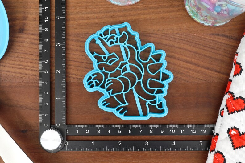 May include: Blue plastic cookie cutter shaped like a cartoon character with spikes on its back.